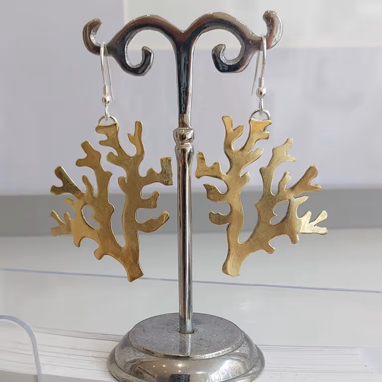 Gold coral design earrings on a display stand