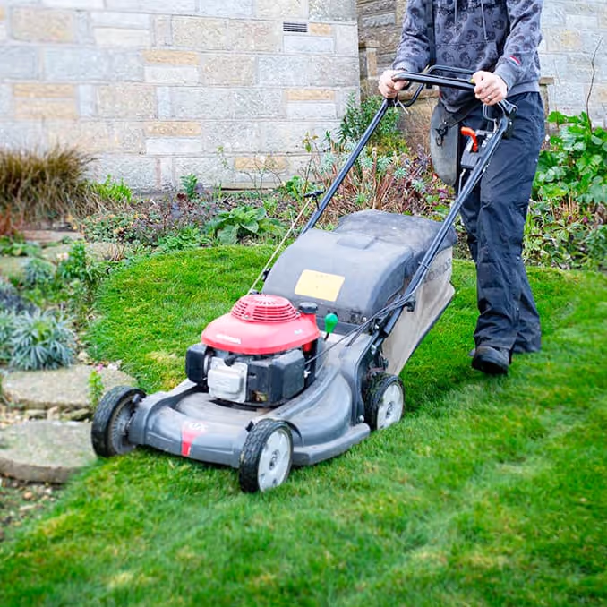 A man cutting a lawn with a lawnmower