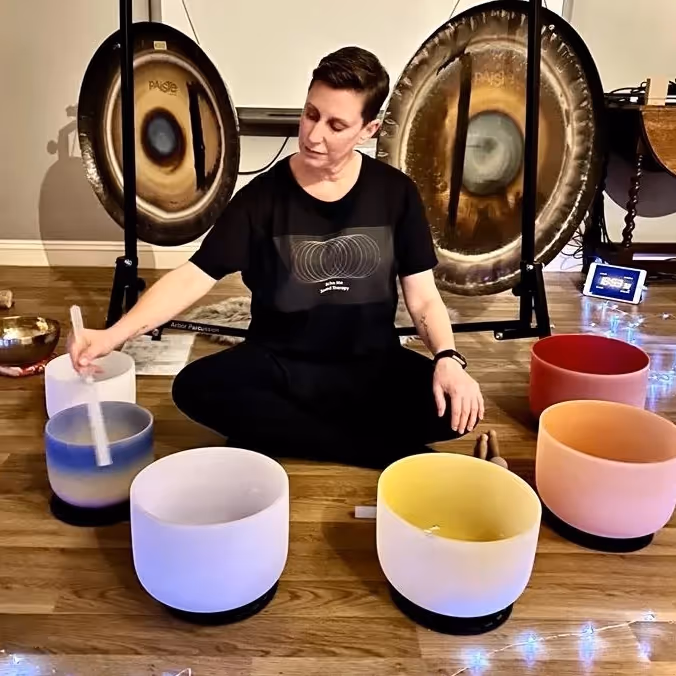 Lady hitting crystal sound bath bowls