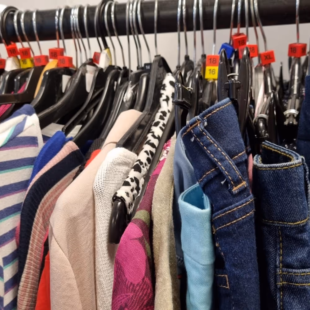 Clothes on hangers on a rail in a charity shop