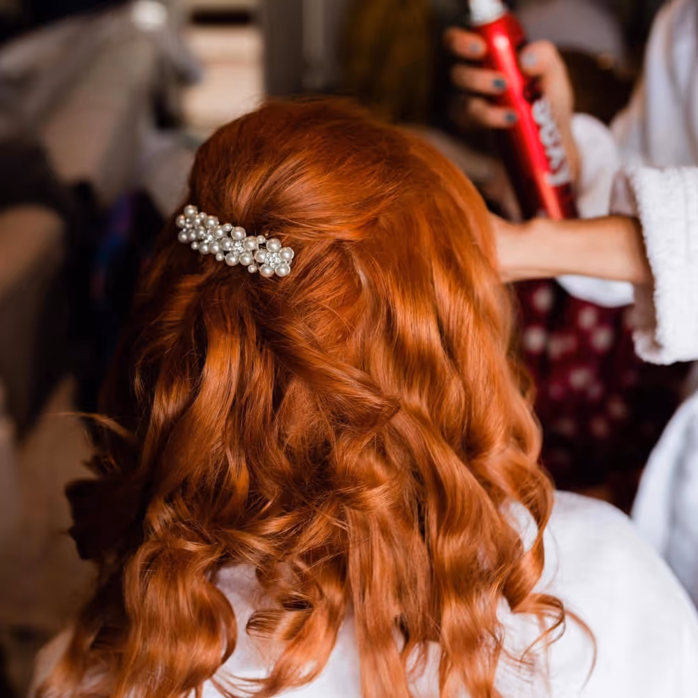 A person with auburn hair in a hairdressers