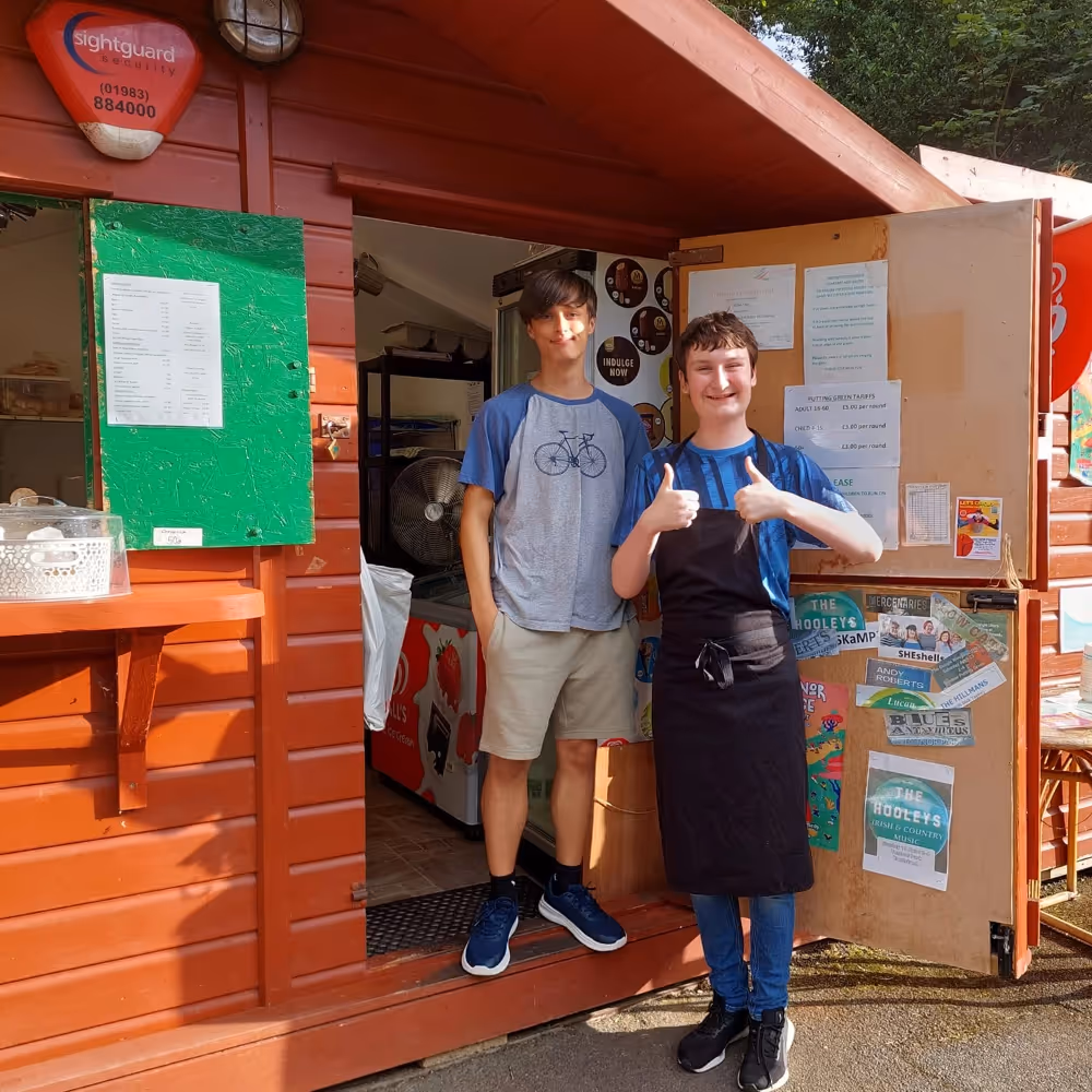 Two members of staff outside their wooden cafe hut