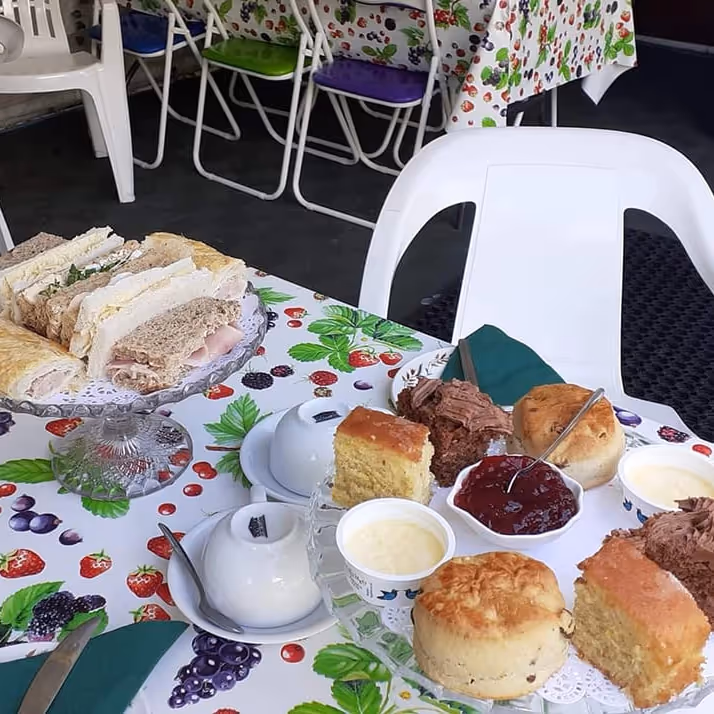 Afternoon tea with sandwiches and scones, set upon a summery tablecloth