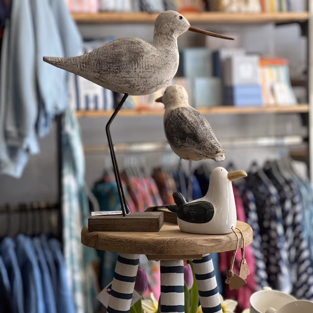 Wooden seagulls sitting on a striped table in a gift shop