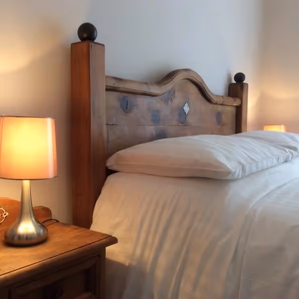 A double bed with a fancy pine headboard and white linen
