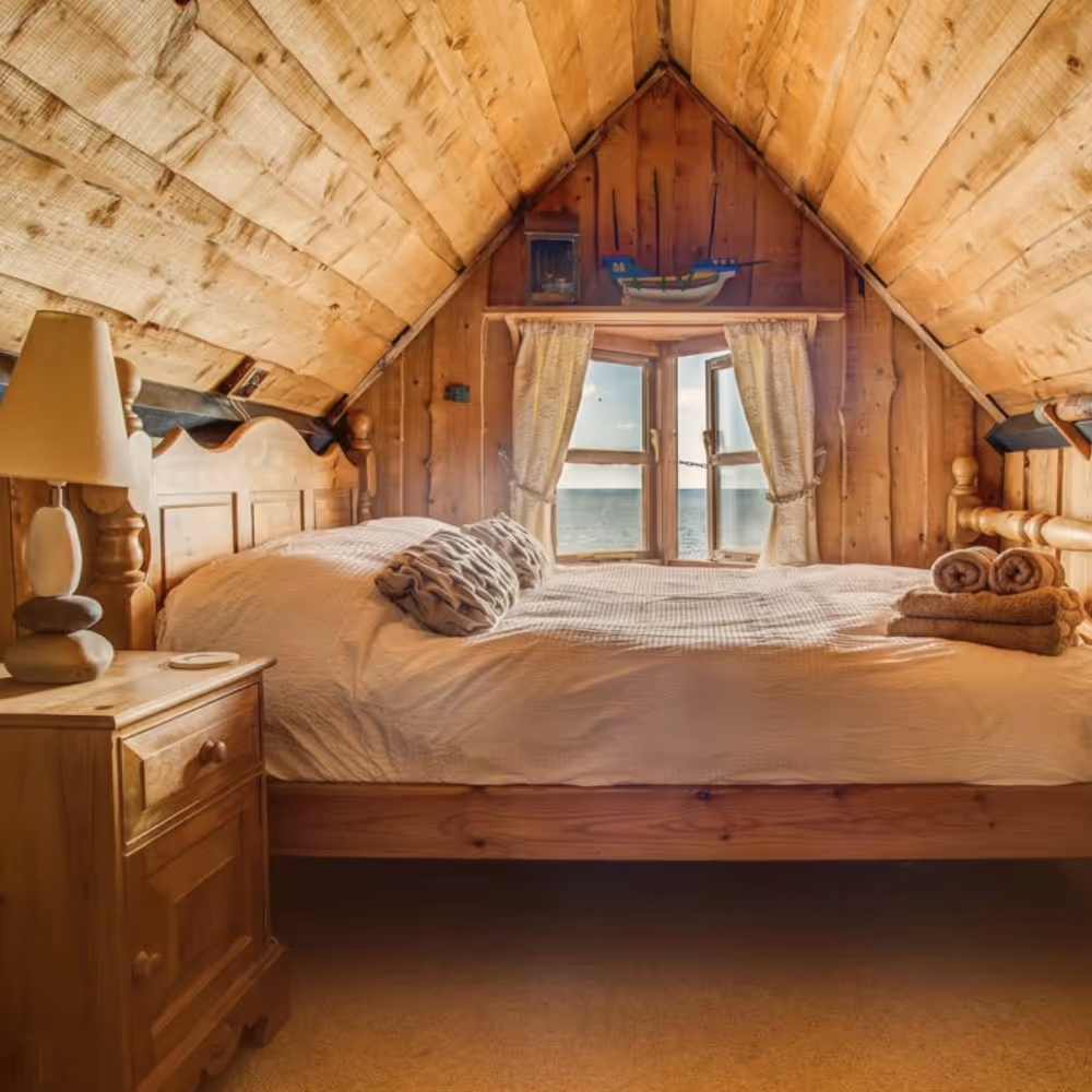 A bedroom in an attic with a pine clad ceiling