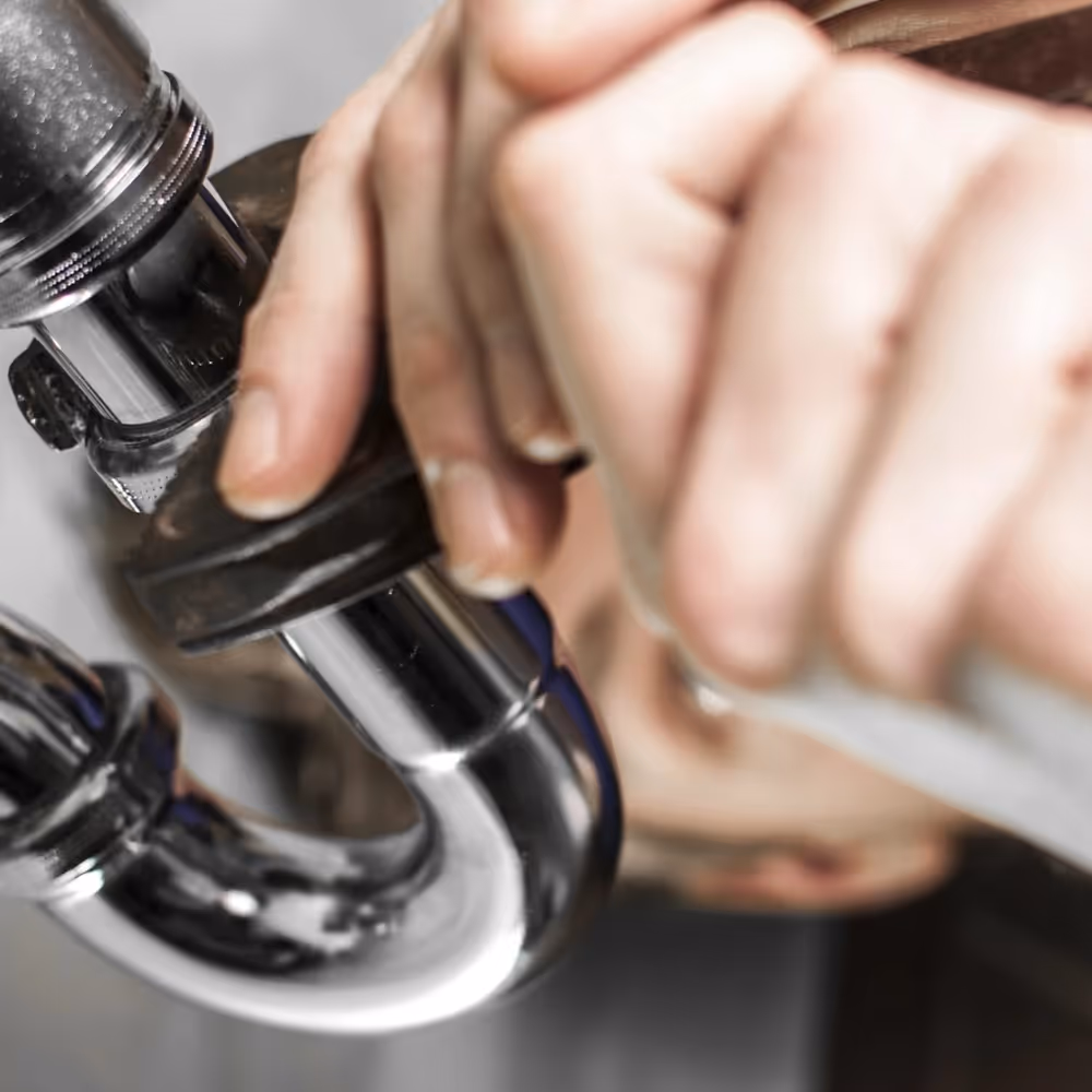 A plumber tightening a sink trap fitting