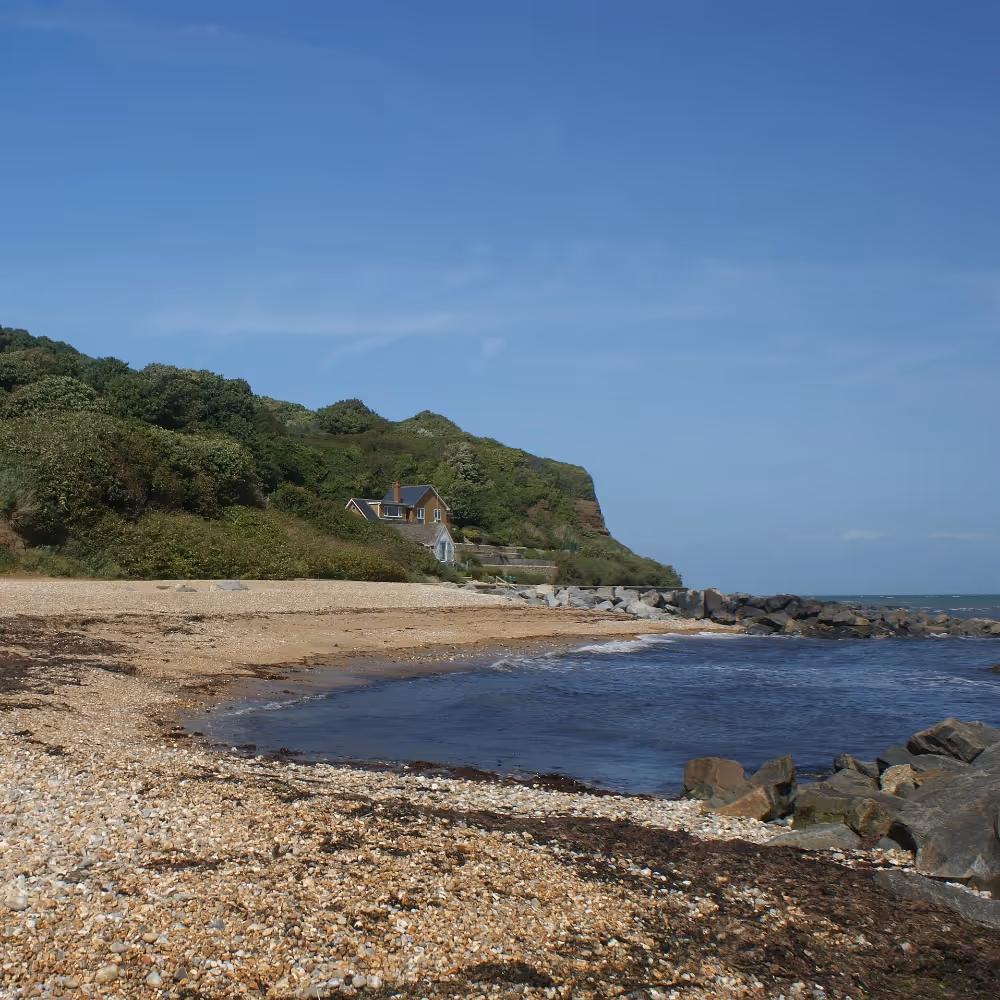 A sandy and shingle cove with a glorious blue sky