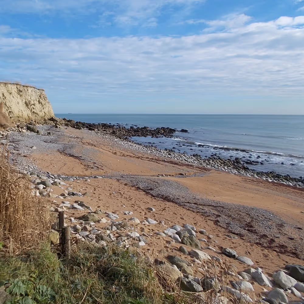 An isolated shingle beach with a blue sky