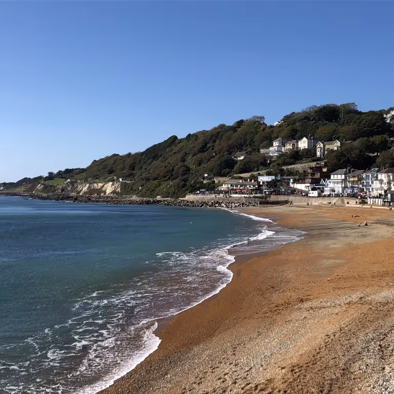A sandy beach looking towards a cliff