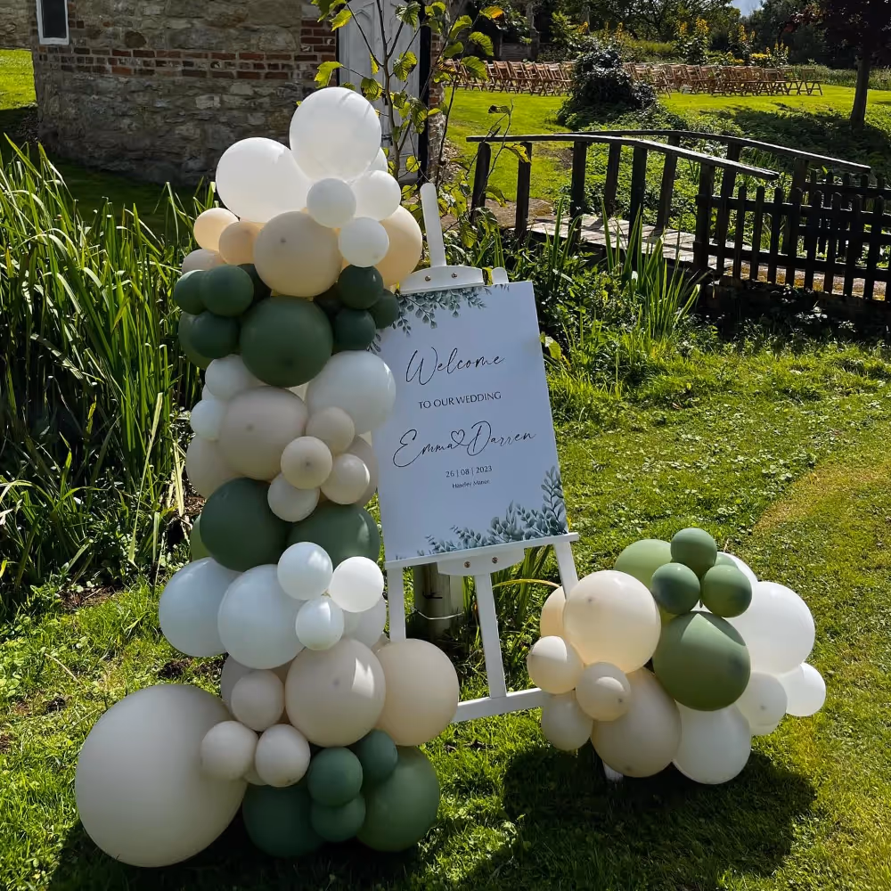 A display of green, cream and white balloons outside a wedding venue