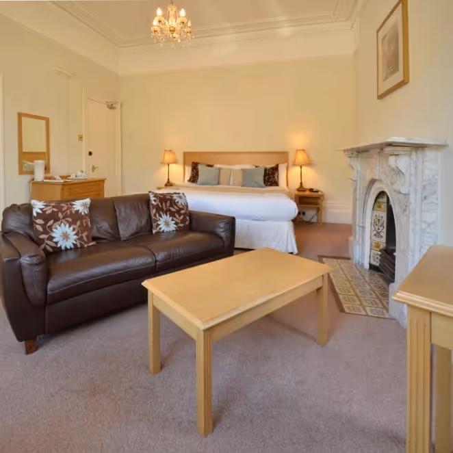 A hotel bedroom with sofas and tables