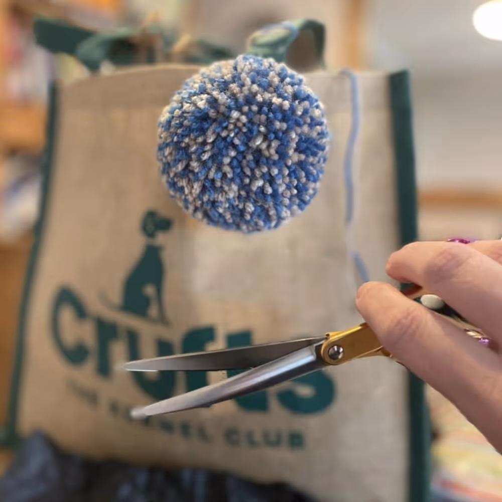A woollen pom pom and scissors