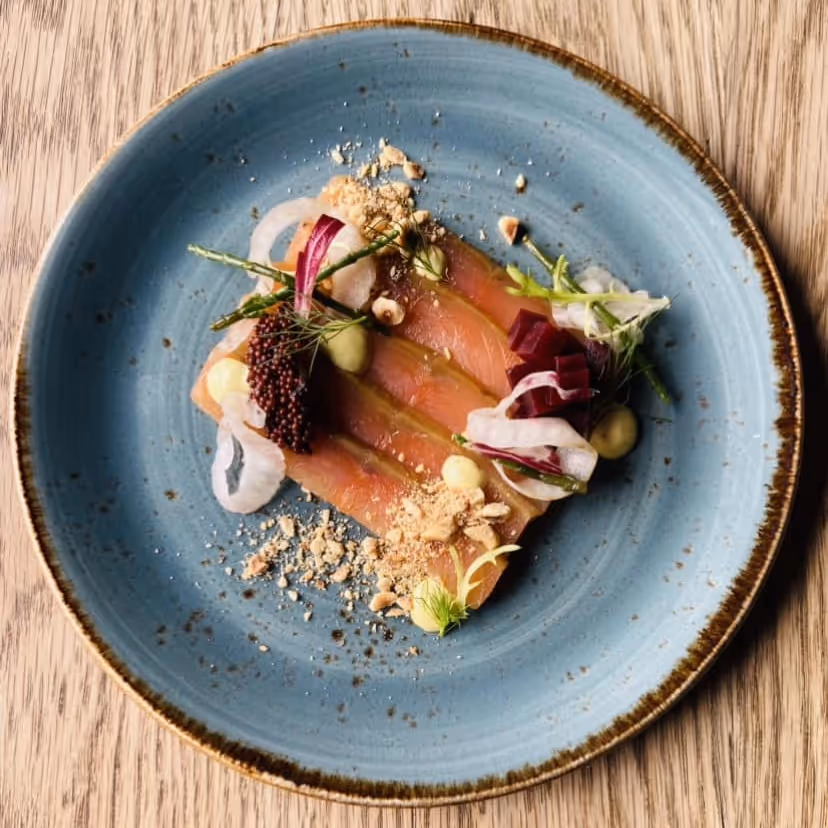 Smoked salmon on toast with salad garnish on a blue plate