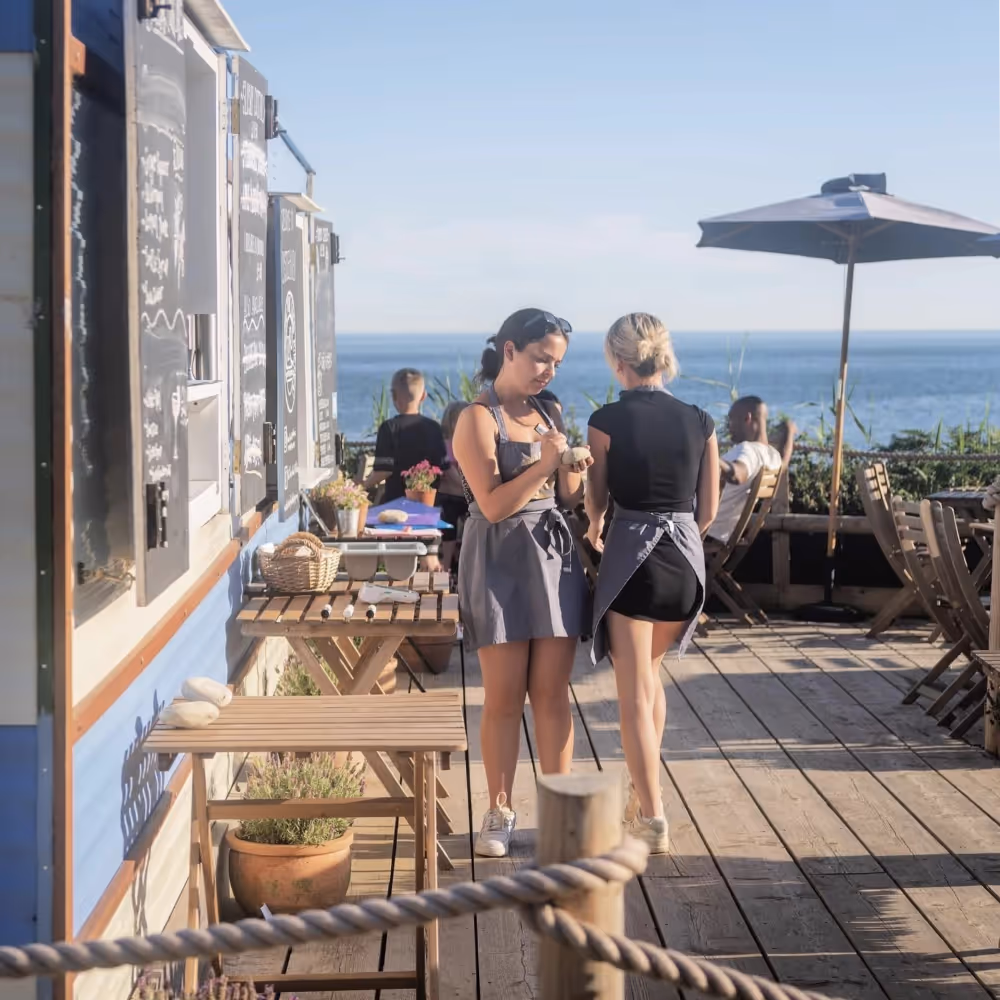 Two waiting staff at a beachside cafe