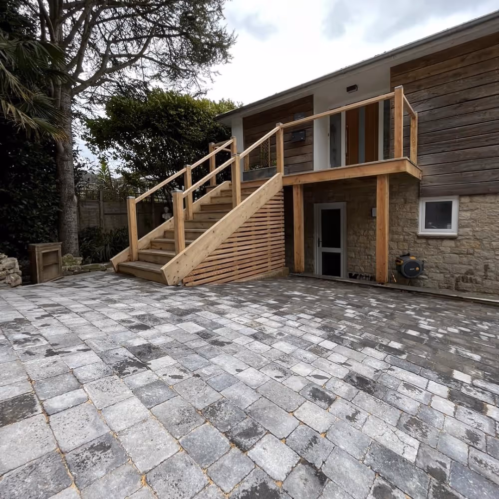 A grey paved driveway leading to a house