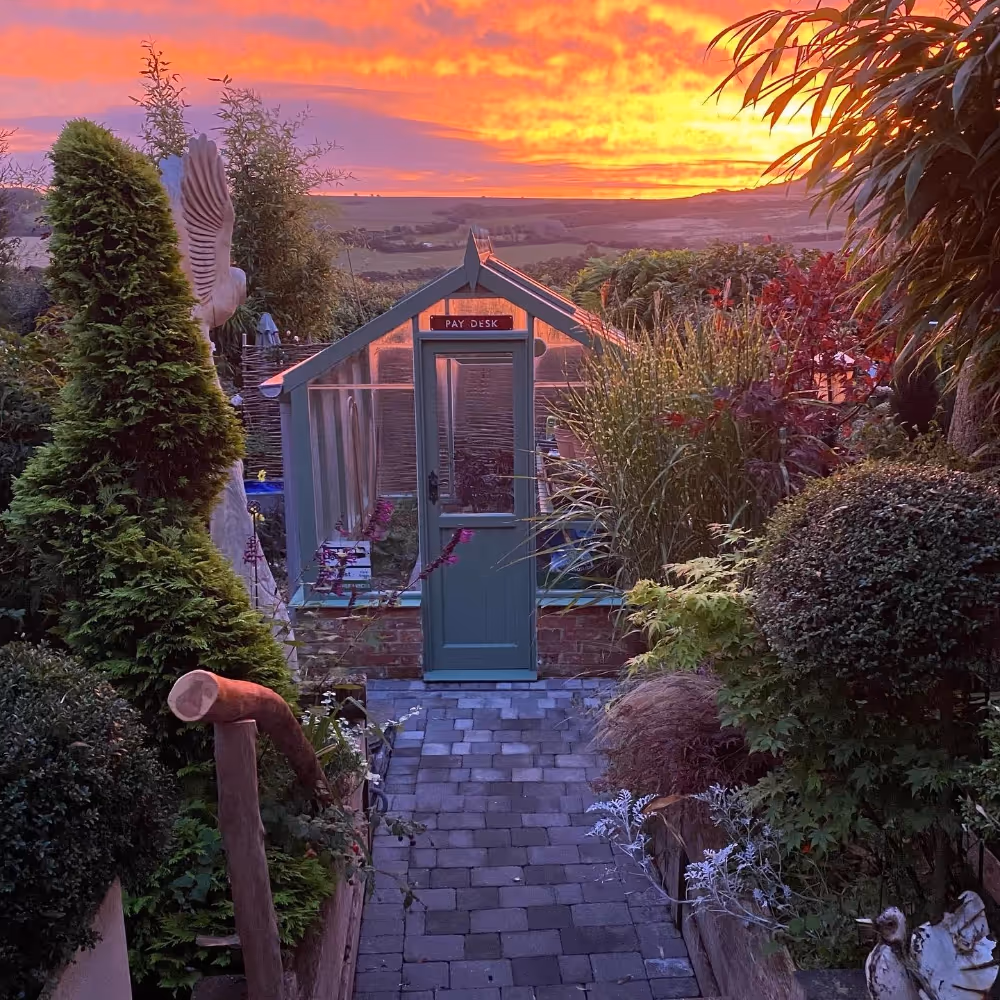 A garden room with a beautiful sunset in the background