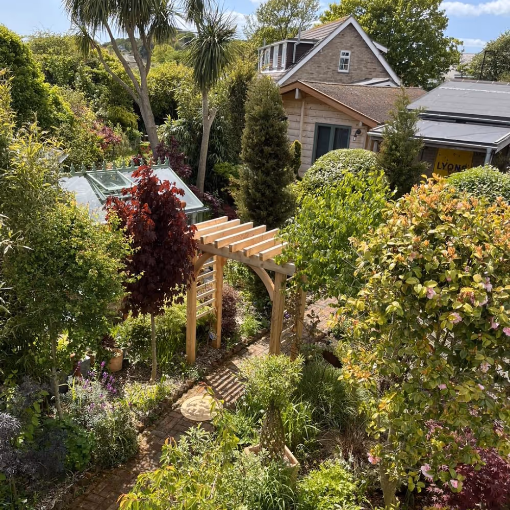 A densely planted garden with a wood arbour