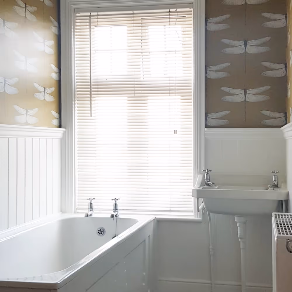 A bathroom with a mustard coloured dragonfly design wallpaper