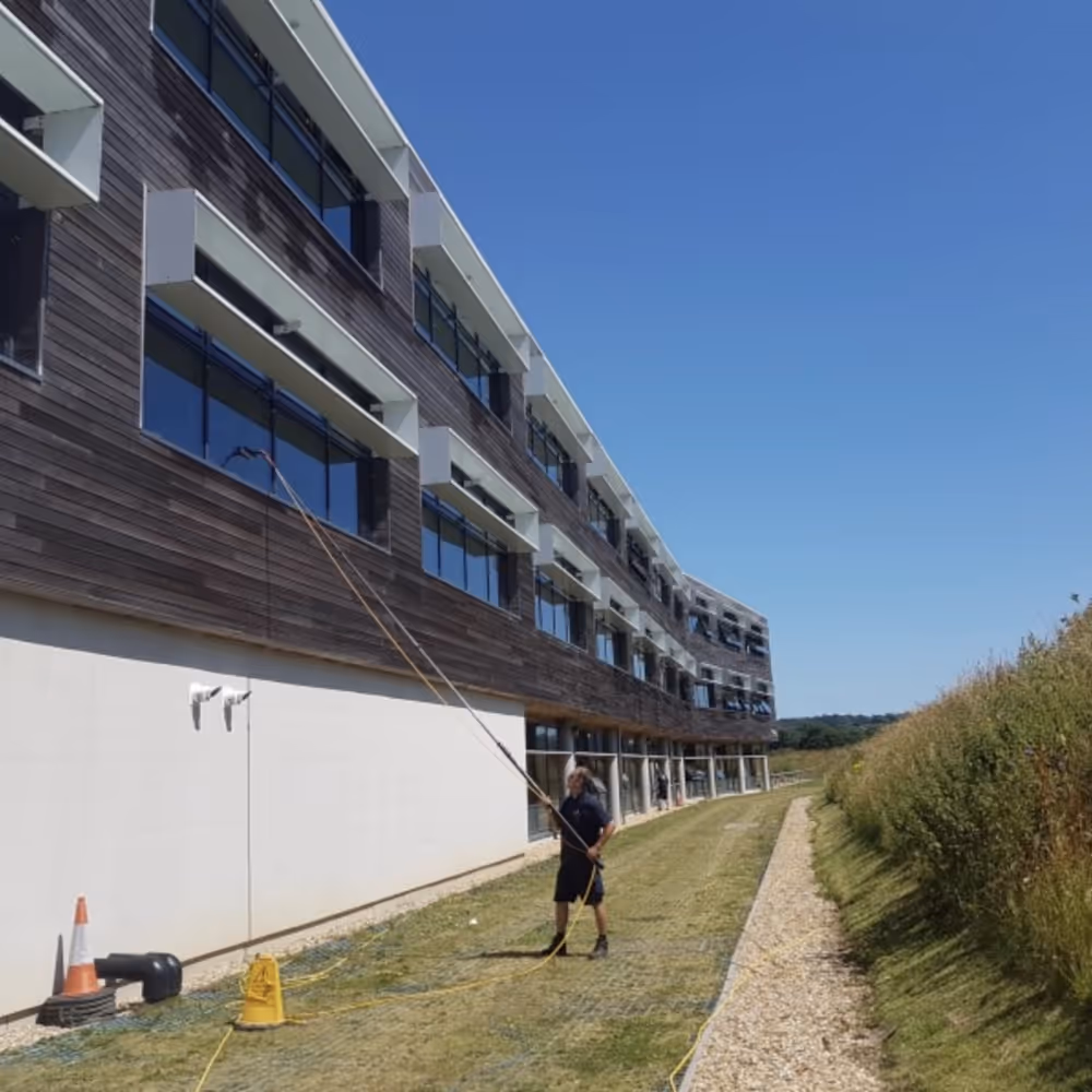 A man cleaning windows of a wooden clad building
