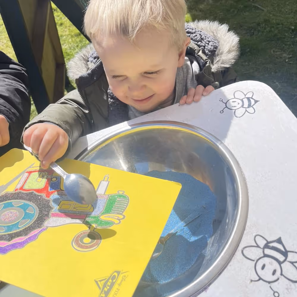 A little boy making a sand art picture