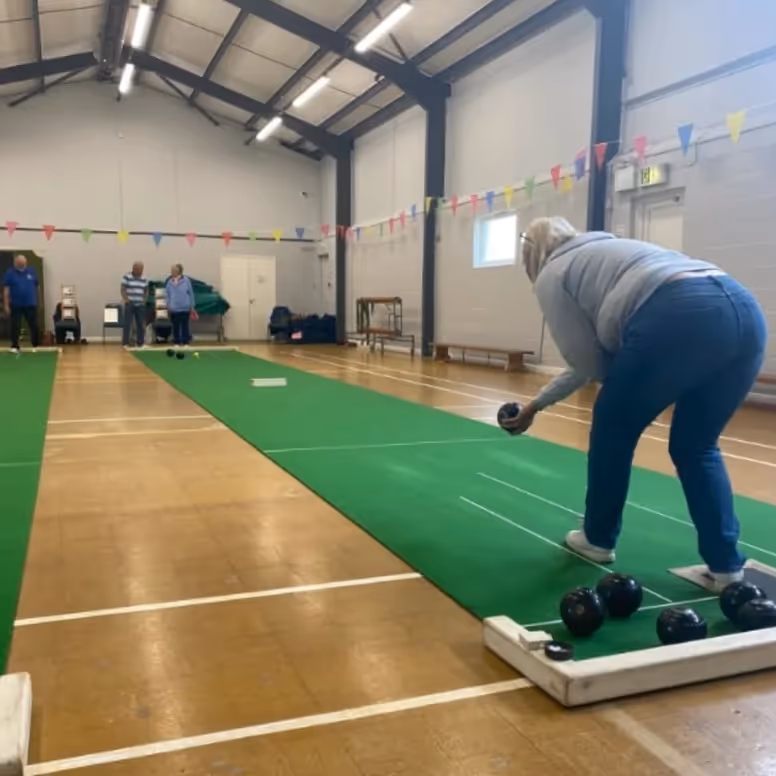 A woman playing short mat bowls