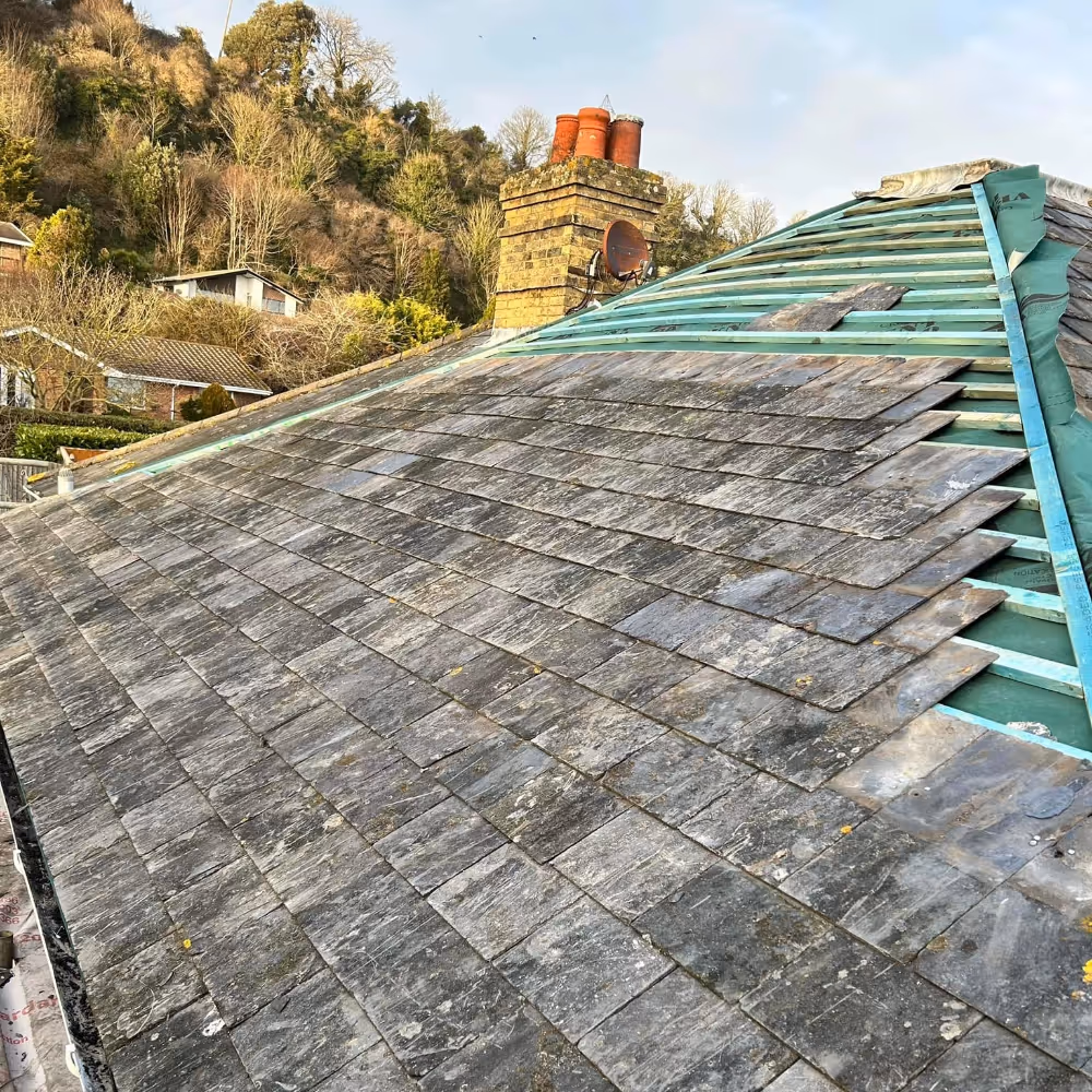 A roof being retiled with reclaimed slate