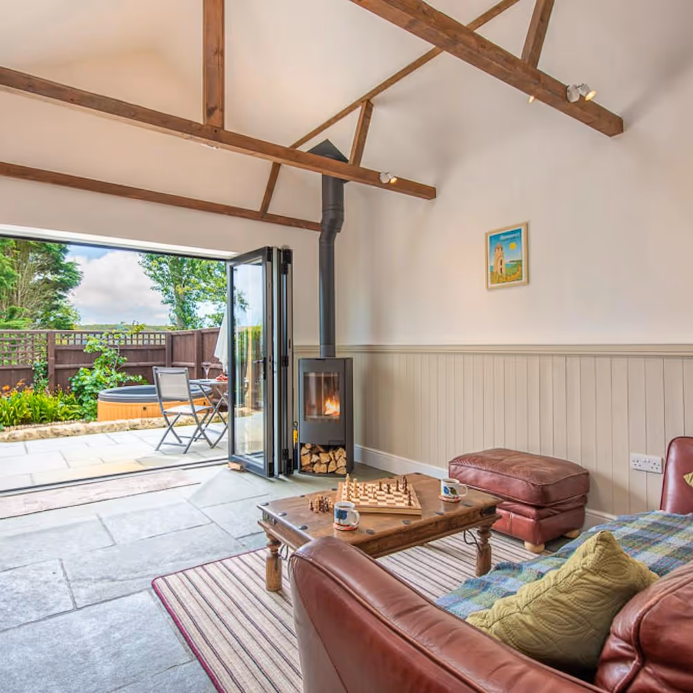 A lofty living room with bi-fold doors looking out to a hot tub