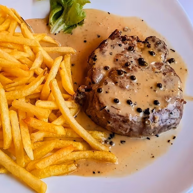 A steak with pepper sauce and skinny fries