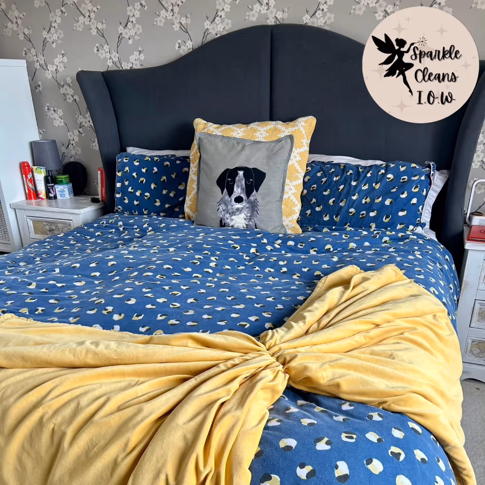 A bed with dark blue bedding and a yellow throw