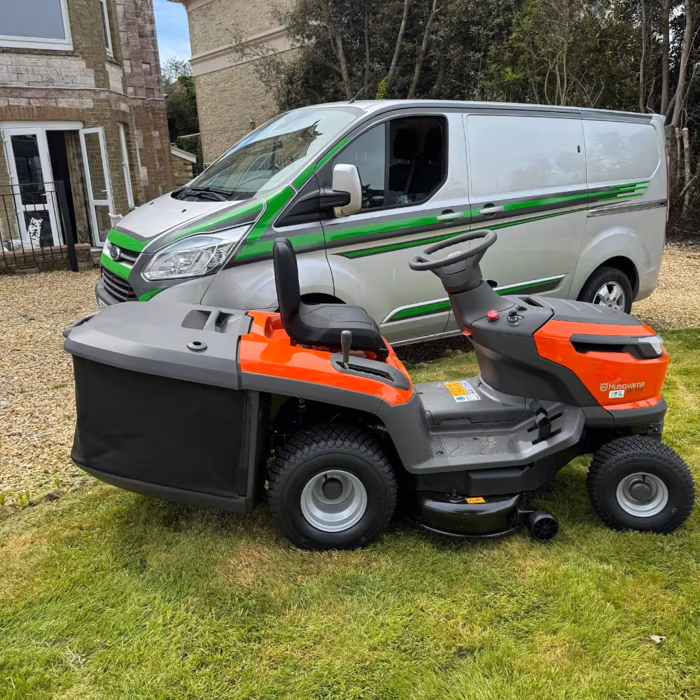 A sit on mower parked by a van