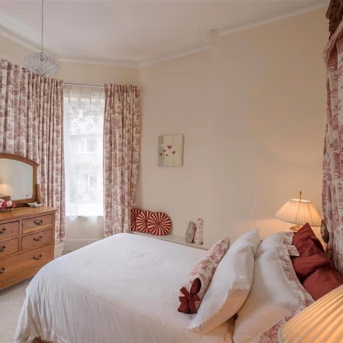 A light bedroom with pink toile curtains