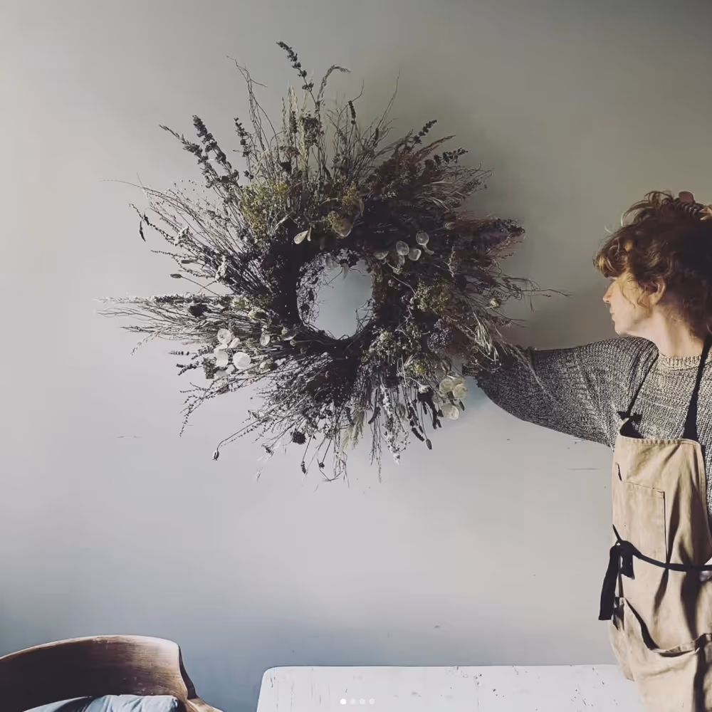 A lady holding a wreath made from dried flowers