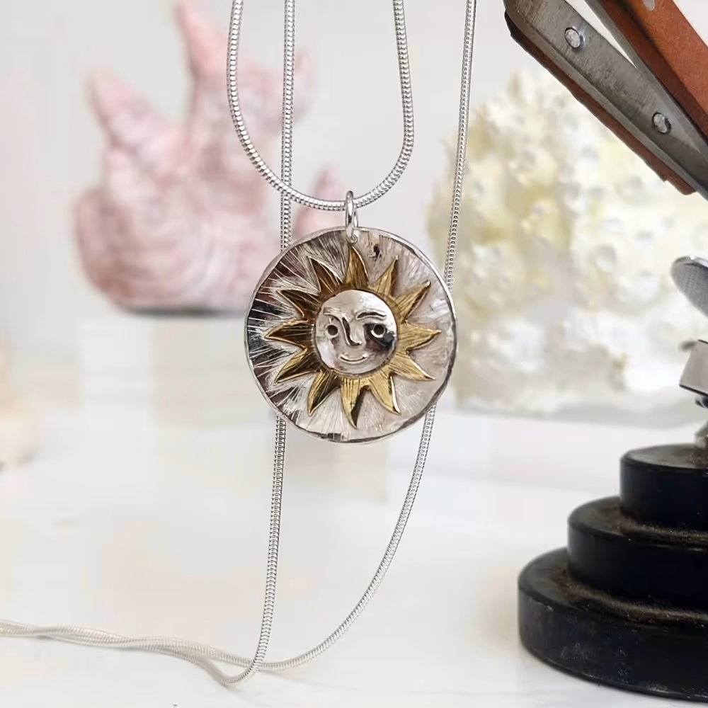 A silver pendant in the style of a sun