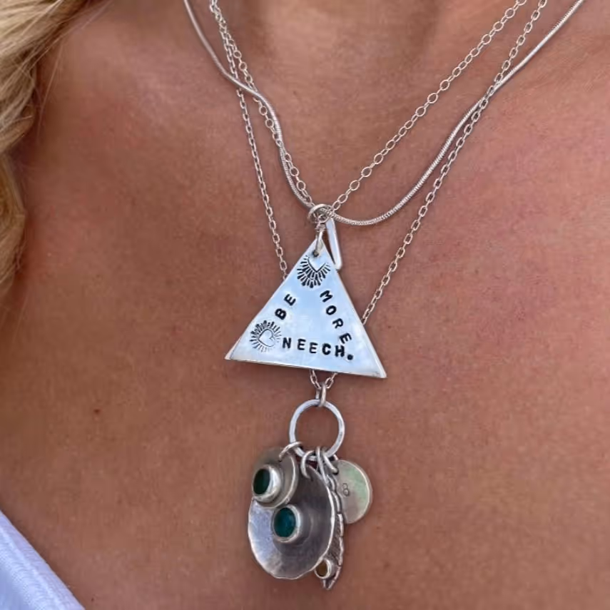 A lady wearing a silver necklace with enamel charms