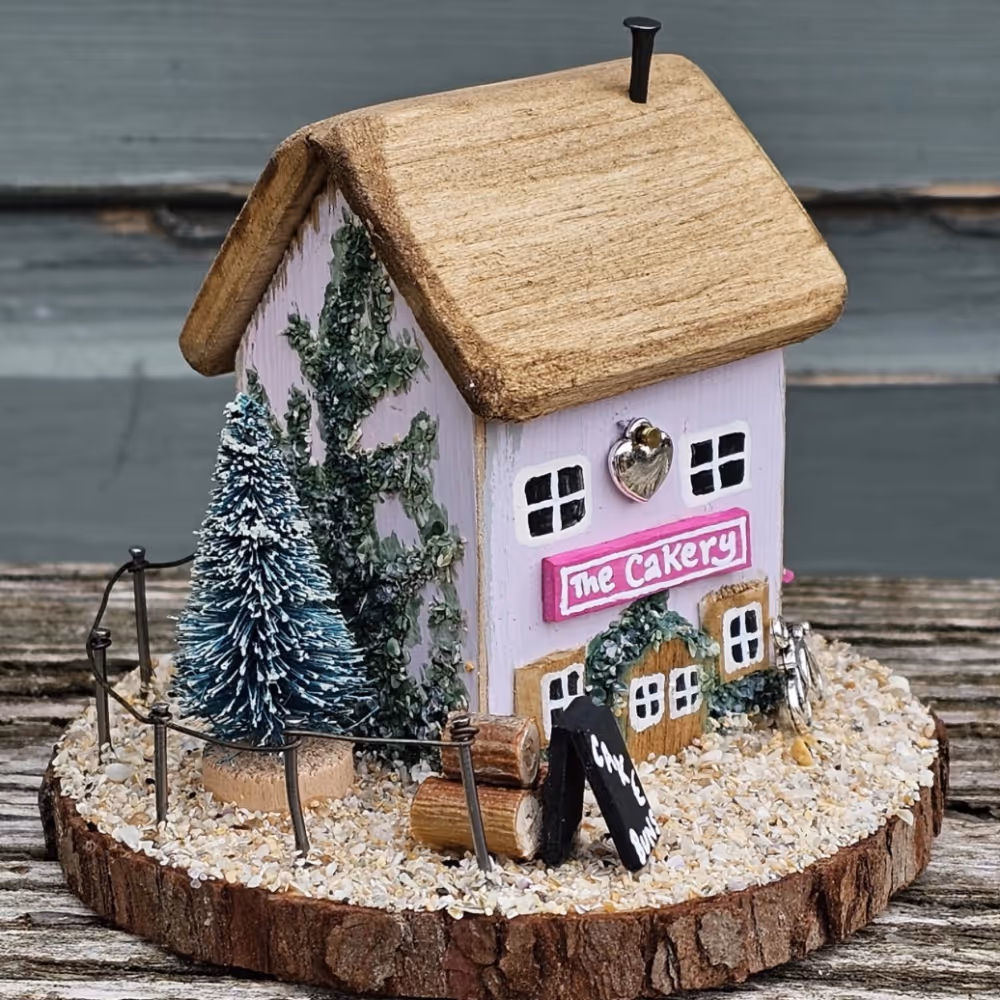 A pink driftwood cottage on a wooden plinth