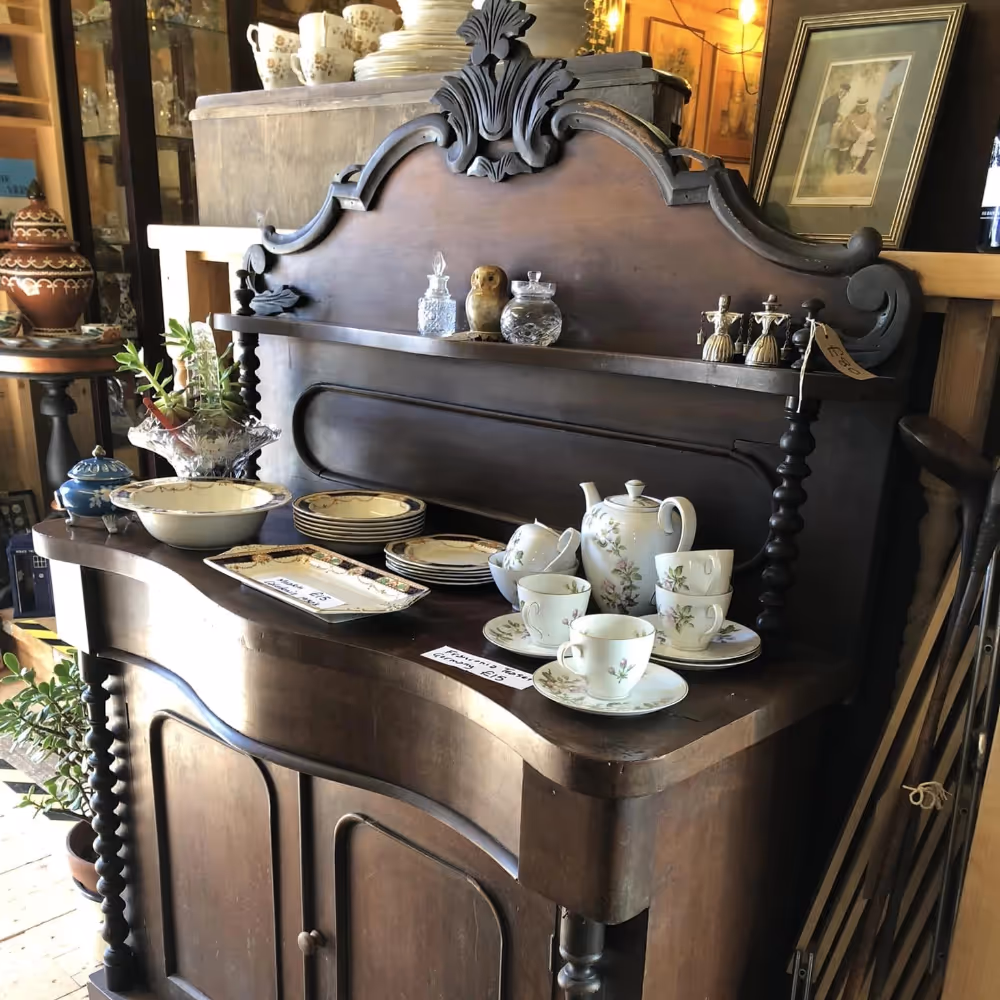 An old ornate sideboard displaying antique china