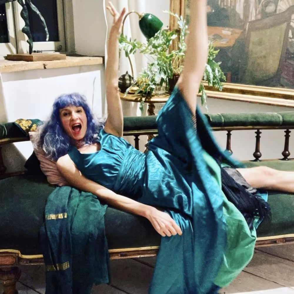 A woman striking a funny pose in an emerald and teal silk dress
