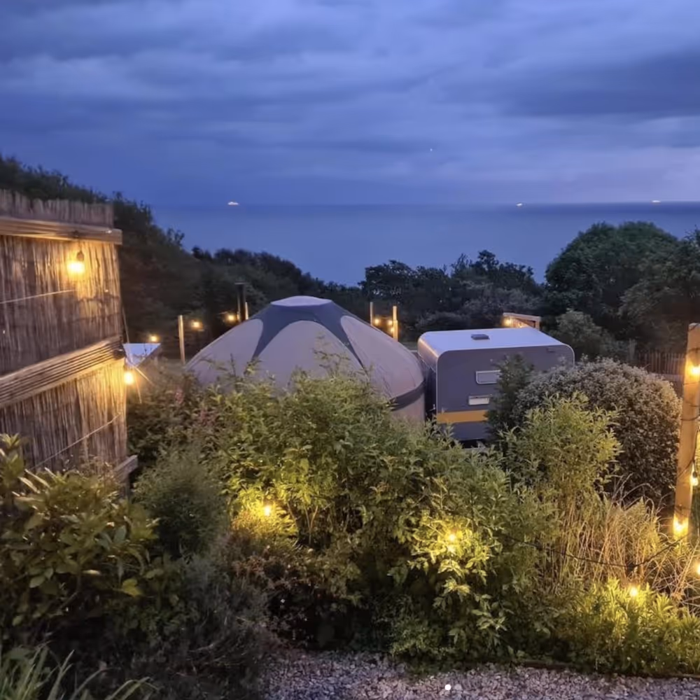 A glamping yurt lit with fairy lights at dusk