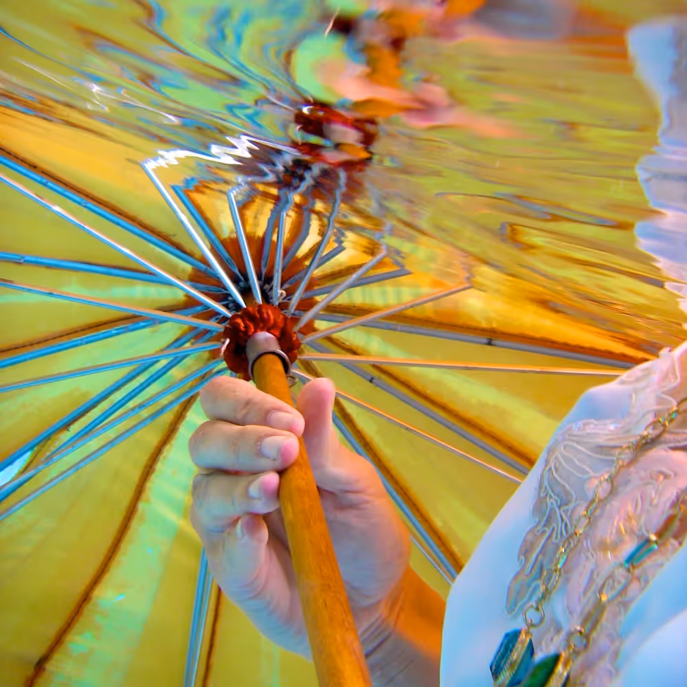A lady holding a vintage umbrella underwater