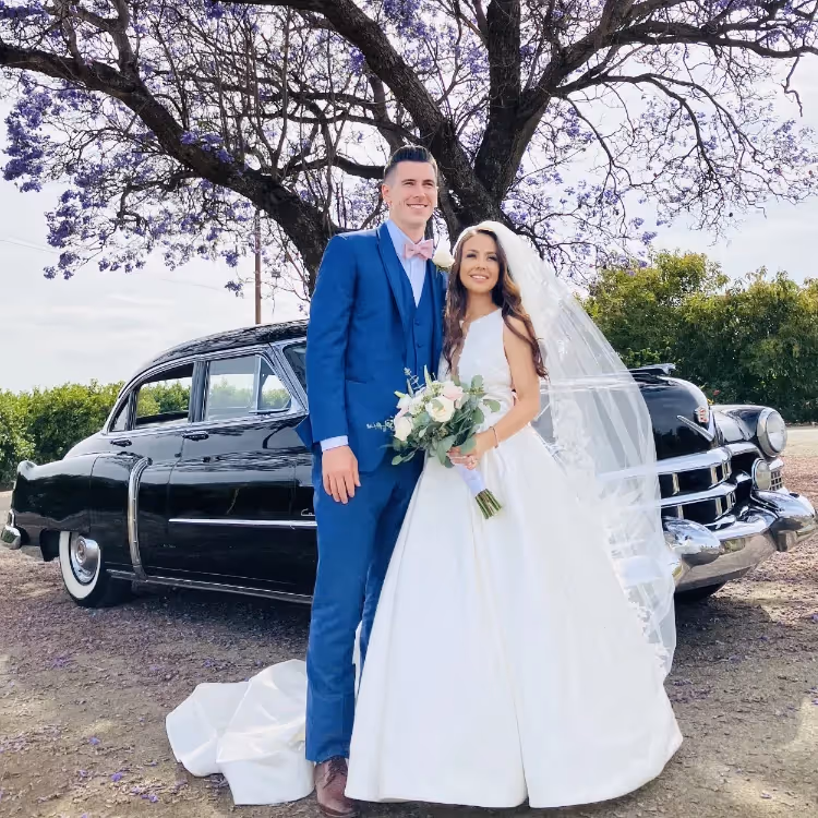 A newly wed couple with their classic wedding car