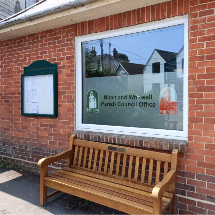 A wooden bench under the window of a red brick building