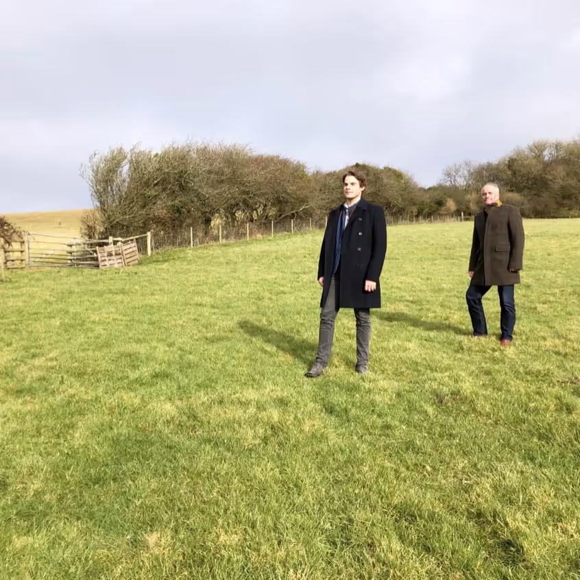 Two men in suits stood in a field