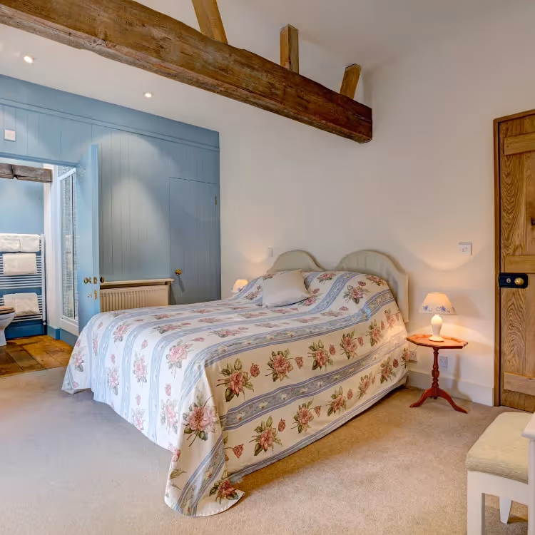 A pretty bedroom with an old oak ceiling beam