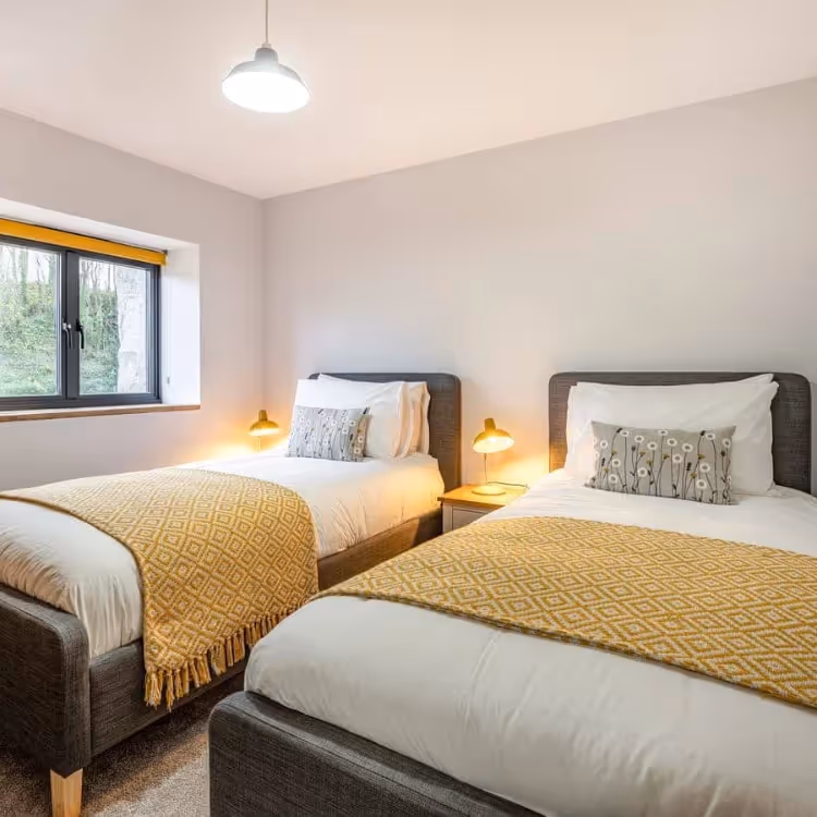 Twin beds in a bedroom with a yellow and grey colour scheme