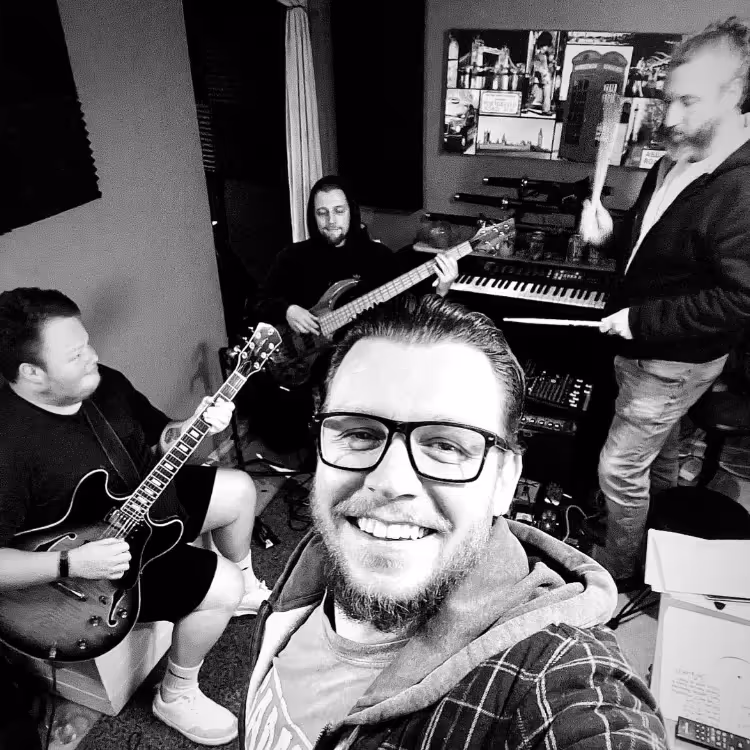 Black and white photo of a band in a rehearsal studio