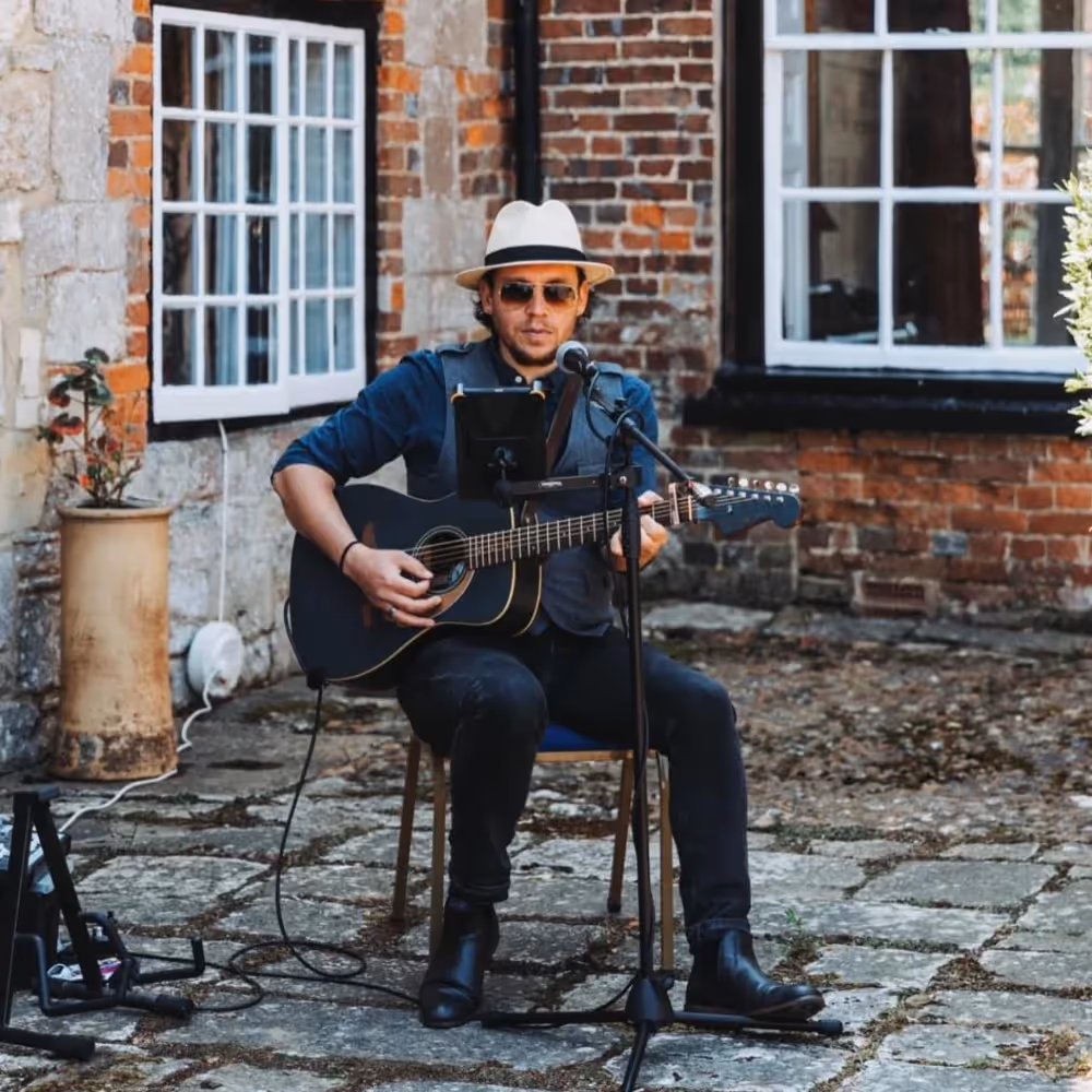 An acoustic guitarist playing in a courtyard