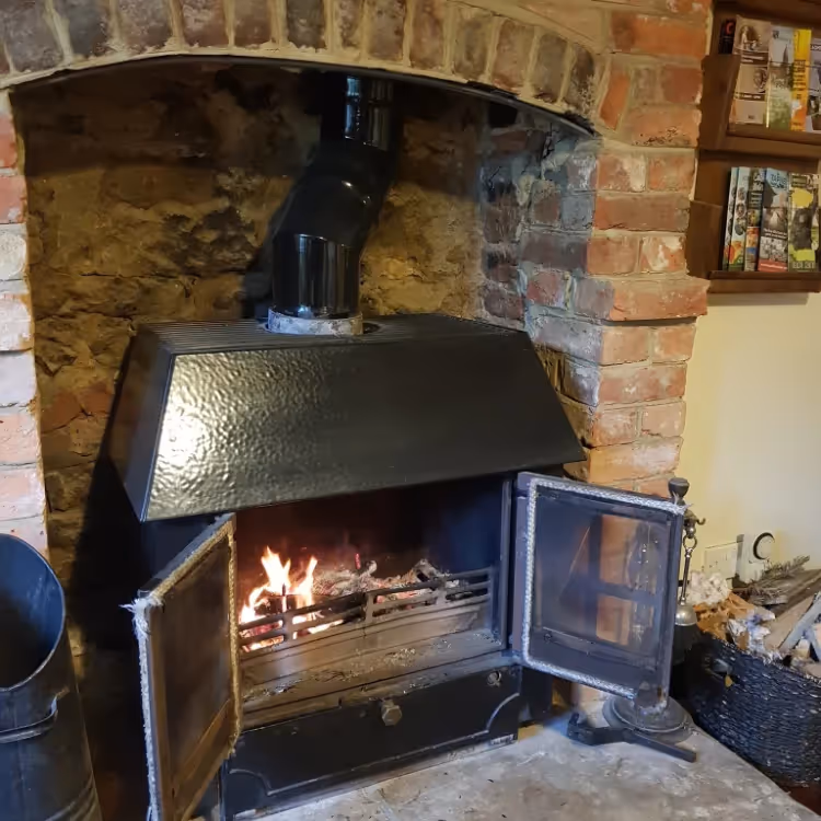 A wood burning stove in a brick fireplace