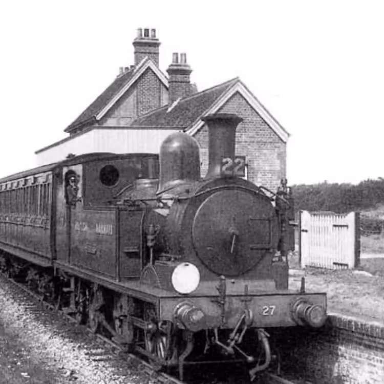 An old photograph of a steam train waiting at a station