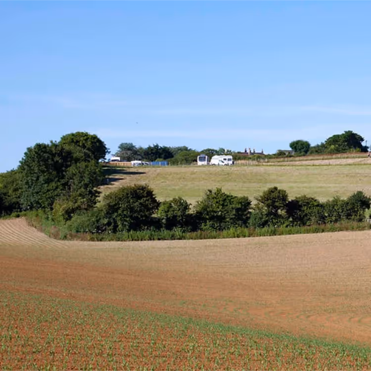 Rolling fields with a campsite in the distance